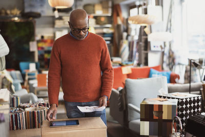 Senior man using digital tablet while reading document at store