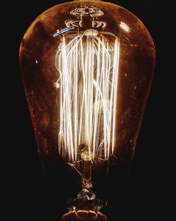 Close-up of illuminated light bulb against black background