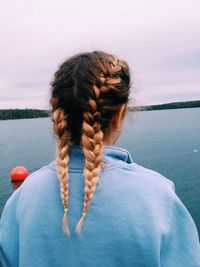 Rear view of woman with braided hair against lake