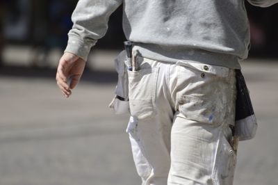 Rear view of man with tools in pocket walking on street