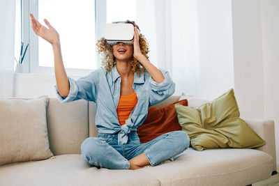 Young woman using phone while sitting on sofa at home