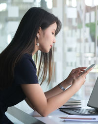 Side view of young woman using mobile phone