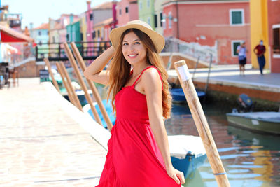 Smiling young woman wearing hat standing by canal