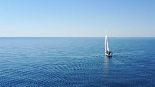 Sailboat sailing in sea against clear sky