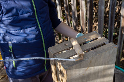 A child paints a wooden box with brushes in the garden