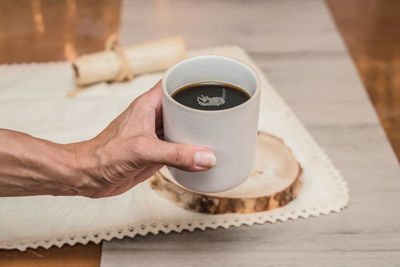 Cropped hand holding coffee on table