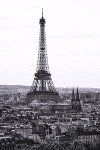 Communications tower in city against sky