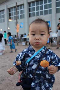 Portrait of cute boy eating food at market