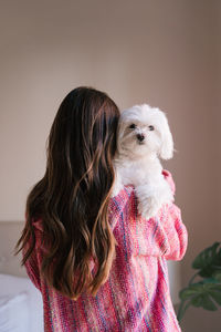 Rear view of woman with dog standing at home