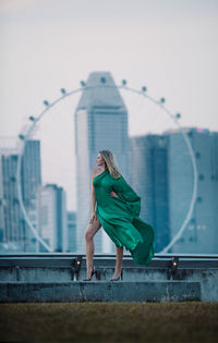 Woman with umbrella on building in city against sky