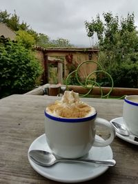 Coffee cup on table against sky