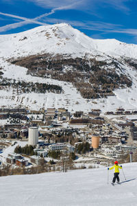 Woman skiing on snow covered field against sky