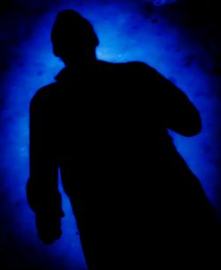 Rear view of silhouette man standing against blue sky