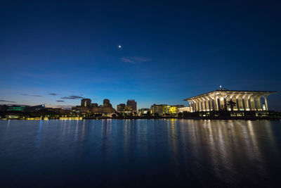 Illuminated tuanku mizan zainal abidin mosque by lake against sky at night