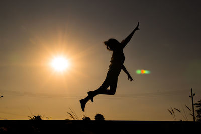 Low angle view of silhouette man jumping against sky during sunset