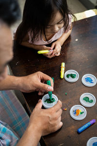 High angle portrait of family painting togeher using glitter glue arts and craft set.