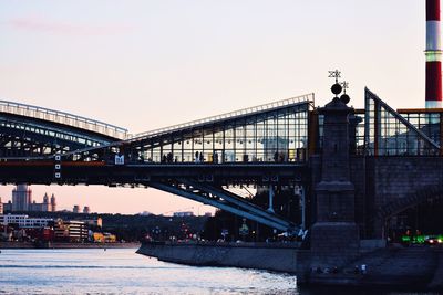 Bridge over river against sky in city