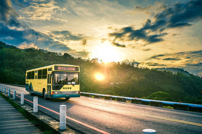 Bus on road against sky during sunset