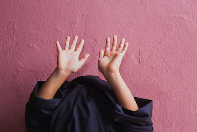 Low section of person standing against wall hiding and show off his hands