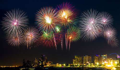 Firework display over illuminated buildings in city at night