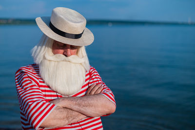 Midsection of woman wearing hat against sea