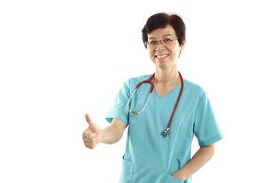 Portrait of smiling mature female doctor standing against white background