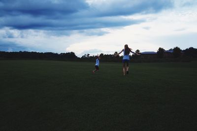 Rear view of young woman with girl playing at park