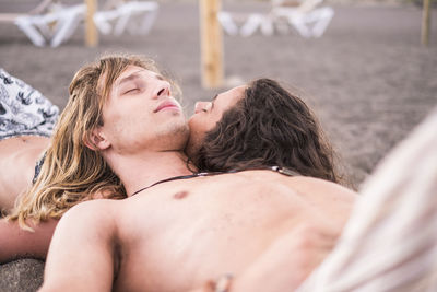 Shirtless couple lying at beach