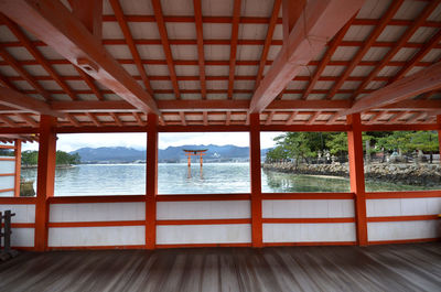Torii gate in sea seen from itsukushima shrine by sea against sky