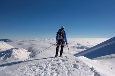 Rear view of people on snowcapped mountains against clear blue sky