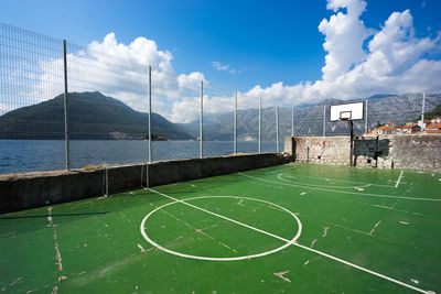 Empty basketball court by sea against sky