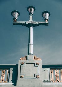 Low angle view of street light by building against sky