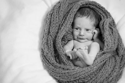 Cute baby boy lying in knitted wool at home