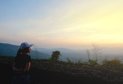 Woman standing on land against sky during sunset