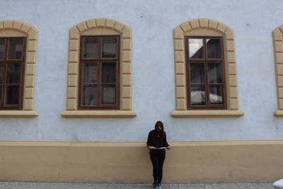 Full length of woman standing against building