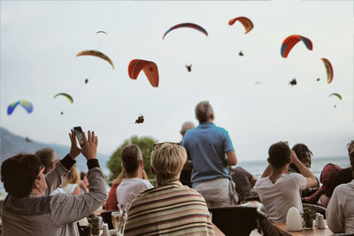 Rear view of people flying against sky