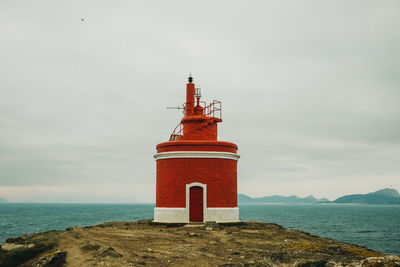 Lighthouse by sea against sky