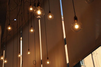 Low angle view of illuminated pendant light hanging from ceiling