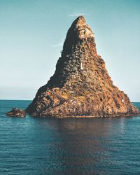 Rock formation in sea against clear sky