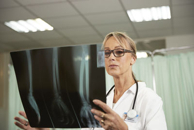 Female doctor with eyeglasses examining x-ray in medical room