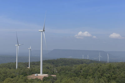 Wind turbines on field against sky