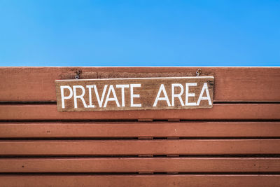 Low angle view of information sign against clear blue sky