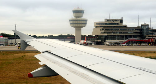 Airplane on airport runway against sky in city