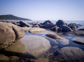 Rocks on beach against clear sky