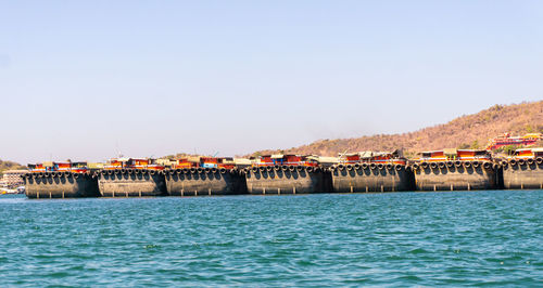 Sea by buildings against clear blue sky