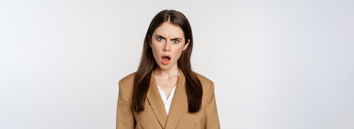 Portrait of young woman standing against white background