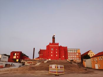 Construction site by buildings against clear sky