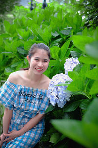Portrait of smiling young woman by plants