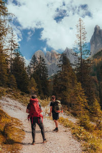 Rear view of people walking on mountain against sky