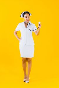 Young woman standing against yellow background